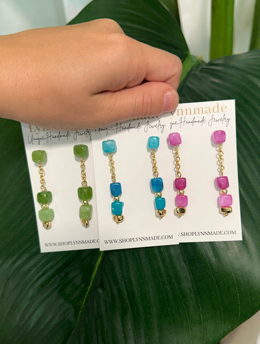 Coastal Gemstone Earrings Dive into summer with the Coastal Gemstone Earrings. Handcrafted with natural Apatite, Amazonian, Vibrant Fuchsia Jade, and lively Peridot green stones, these earrings capture the essence of the sea and sun. Their vibrant hues and elegant design make them the perfect accessory for your summer vacation, adding a touch of coastal charm to any outfit. Embrace the season's beauty with these stunning statement pieces.